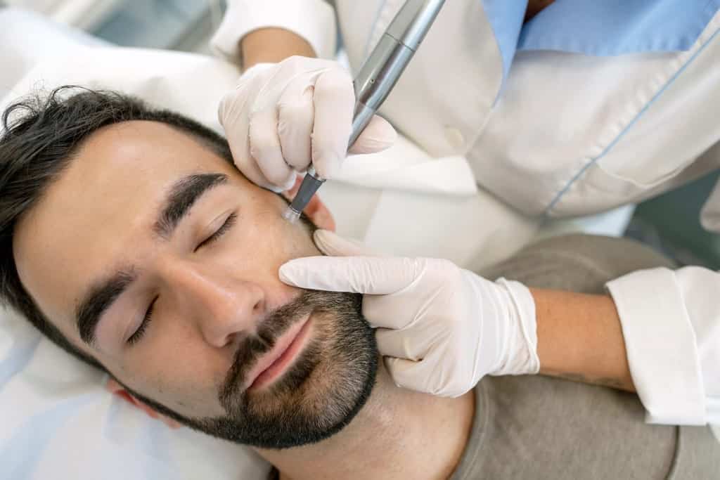 Young man in medical spa having microdermabrasion procedure performed