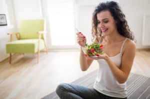 Woman eating healthy salad after working out at home 300x197 1