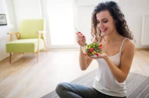 Woman eating healthy salad after working out at home