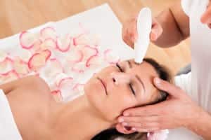young female patient lying down undergoing microdermabrasion, med spa professional holding device on her forehead