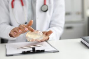 A doctor holding a silicone breast implant in their hand