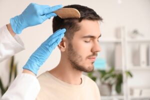 Doctor combing young man's hair in clinic