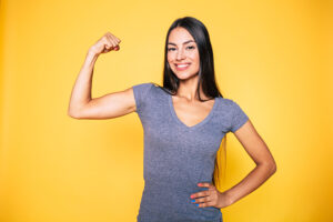 Latina woman flexes her toned arm after removing loose skin and fat with arm lift and liposuction