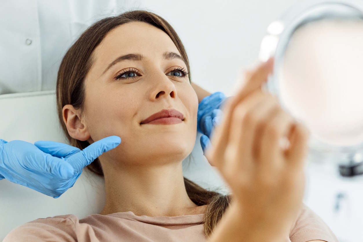 Beautiful smiling Woman having Facial Treatment looking at mirror